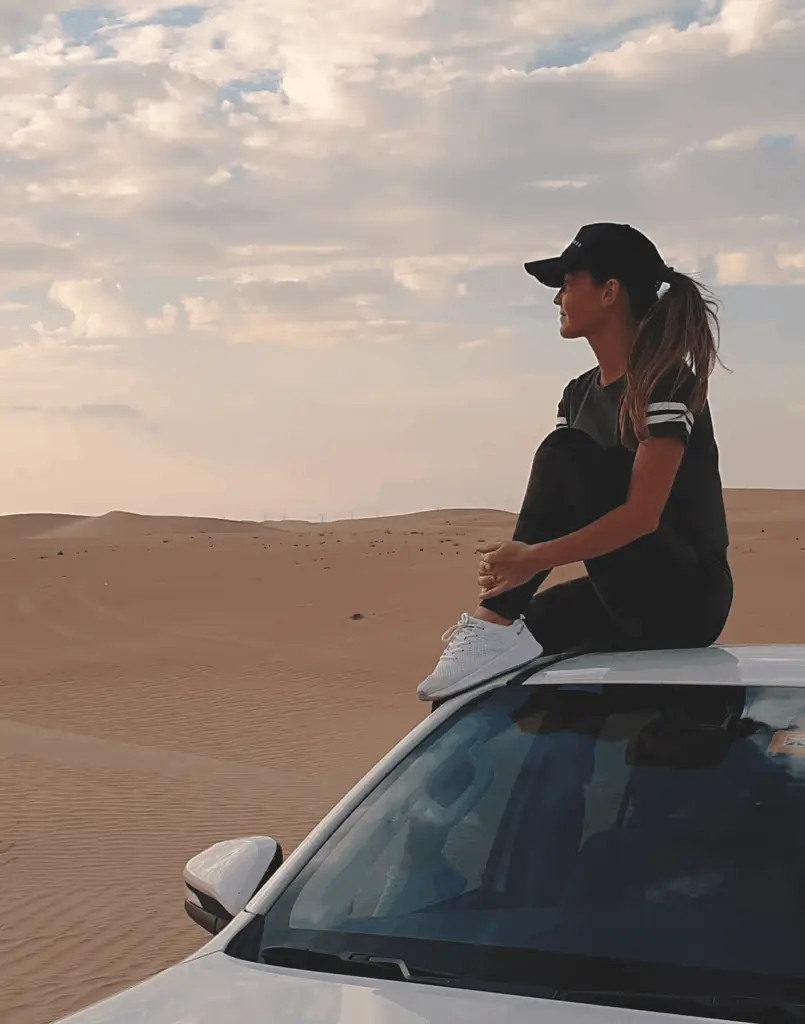 Girl in the desert using Otto’s flexible car subscription to watch the Dubai sunset
